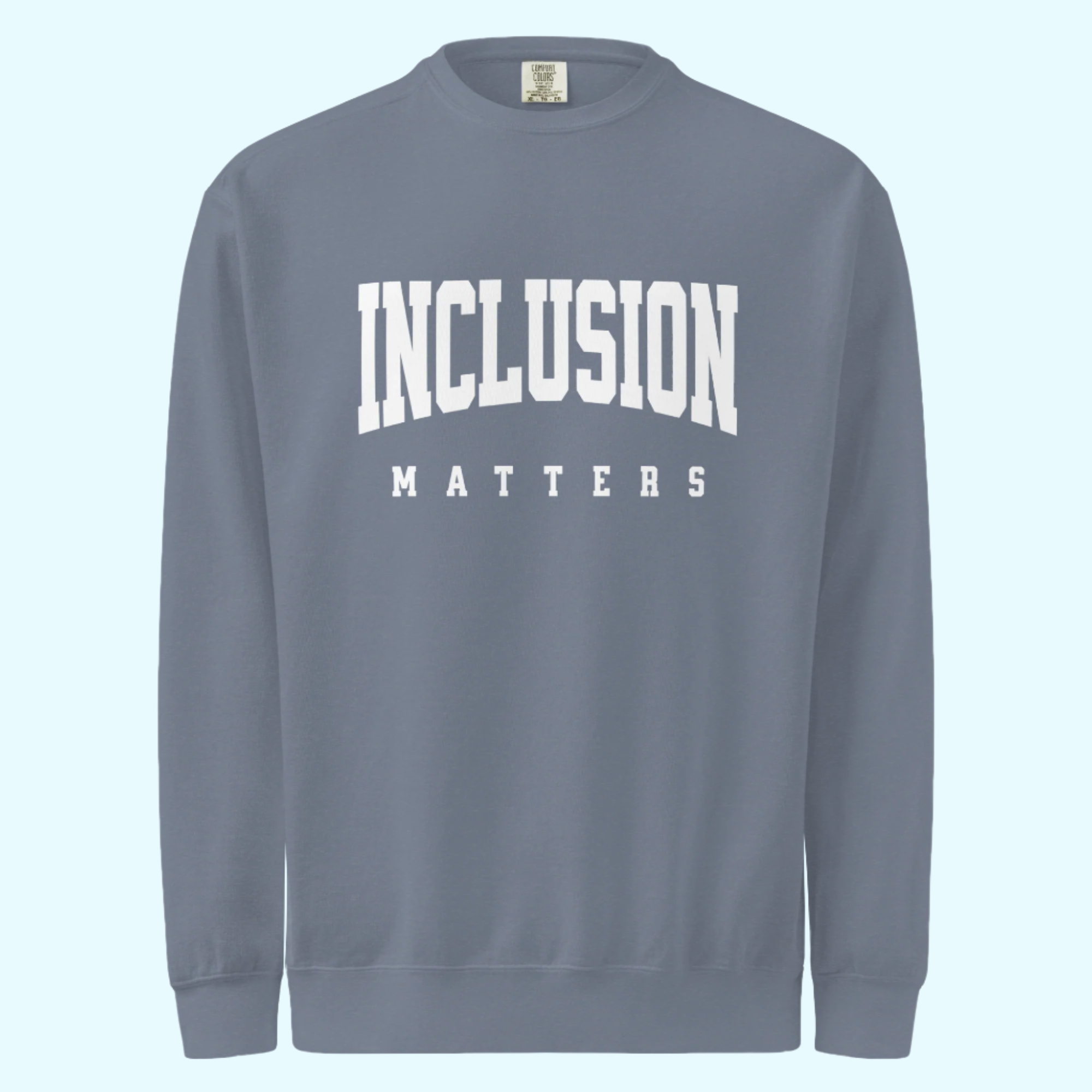 Solo mockup of the “Inclusion Matters” sweatshirt in a faded blue jean Comfort Colors style. The sweatshirt features bold white text centered on the chest, with a relaxed, cozy fit and vintage-washed look displayed against a neutral background.