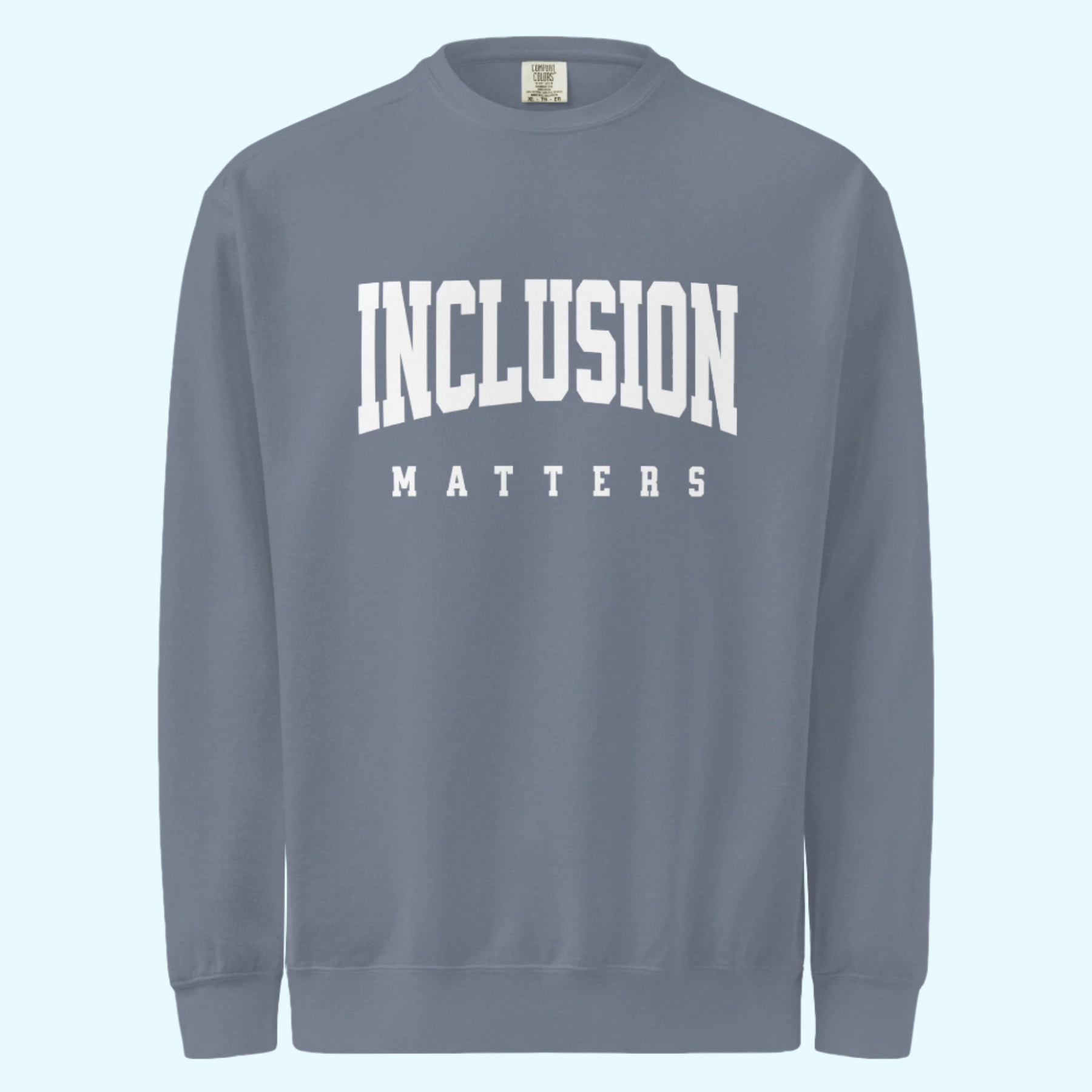 Solo mockup of the “Inclusion Matters” sweatshirt in a faded blue jean Comfort Colors style. The sweatshirt features bold white text centered on the chest, with a relaxed, cozy fit and vintage-washed look displayed against a neutral background.