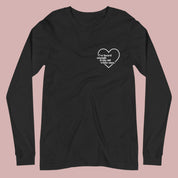Flat lay of a black long-sleeved t-shirt on a white background. A small white heart in the upper left chest area surrounds the text: “I’ve heard enough from old white men.”