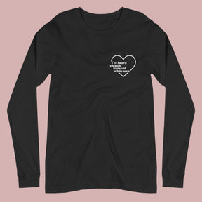 Flat lay of a black long-sleeved t-shirt on a white background. A small white heart in the upper left chest area surrounds the text: “I’ve heard enough from old white men.”