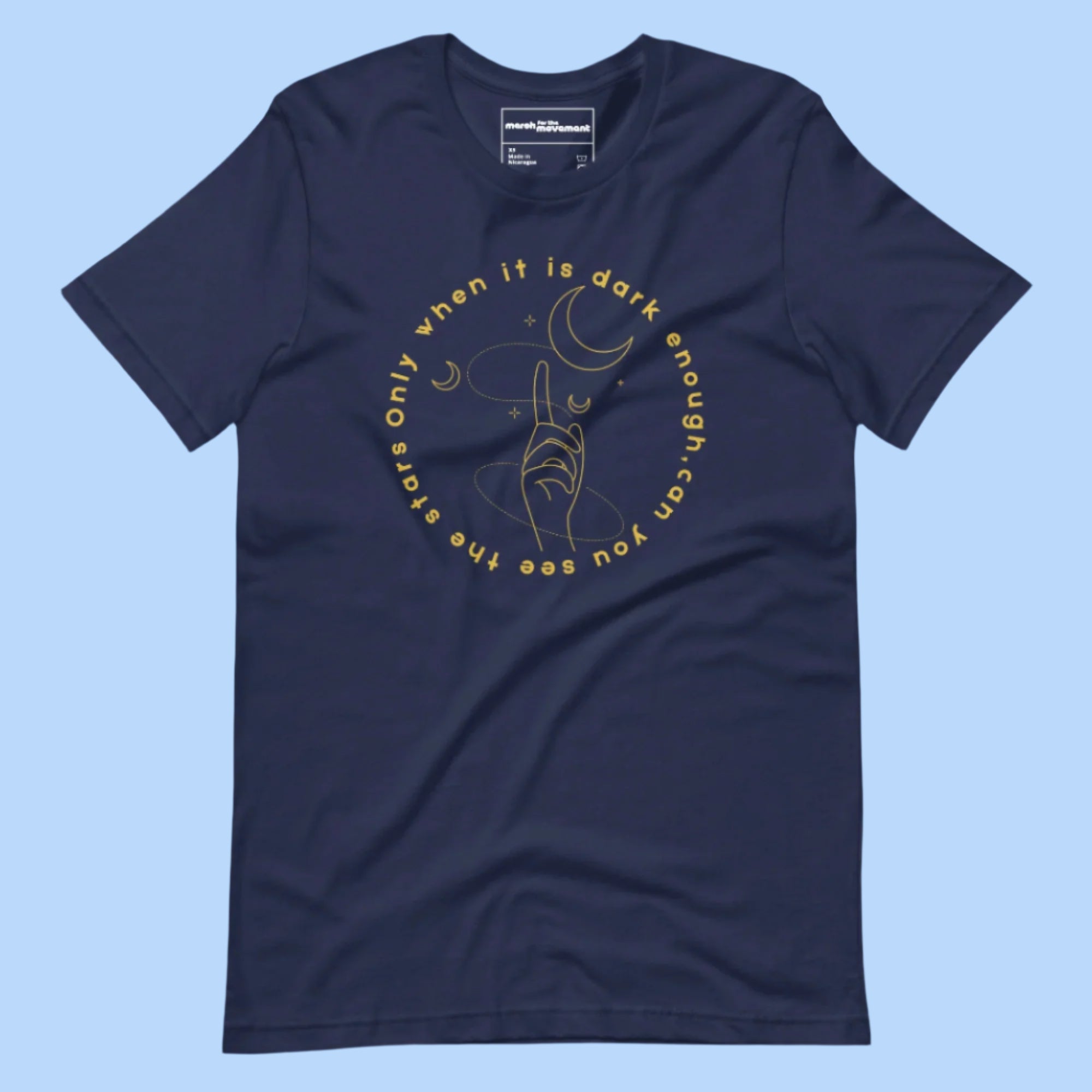 Flat lay of a T-shirt with the quote 'Only when it is dark enough can you see the stars' printed across the front.