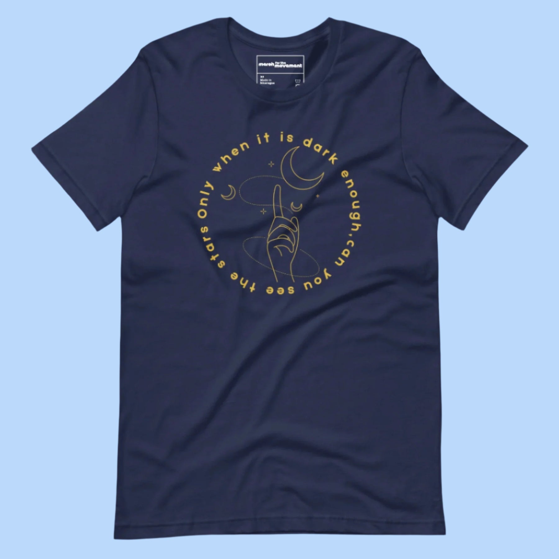 Flat lay of a T-shirt with the quote 'Only when it is dark enough can you see the stars' printed across the front.