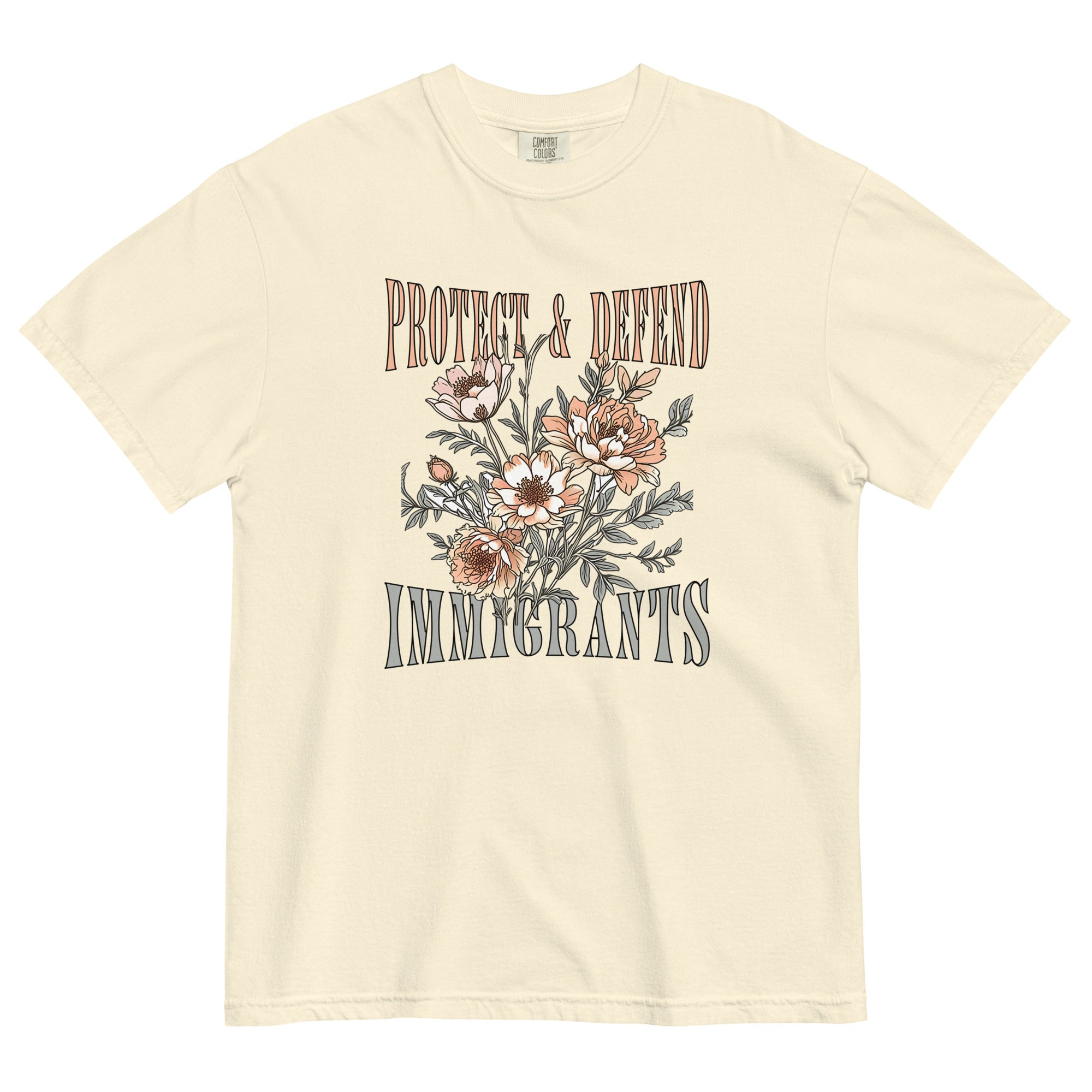 Ivory-colored unisex Comfort Colors t-shirt with the phrase “Protect & Defend Immigrants” in lightweight, uppercase font, surrounding a large, detailed flower graphic in the center. The design is bold yet soft, printed on a heavyweight cotton shirt with a relaxed fit.