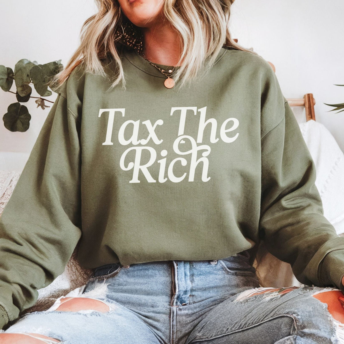 Tax the Rich sweatshirt in military green worn by a woman — bold political statement sweatshirt supporting economic justice.
