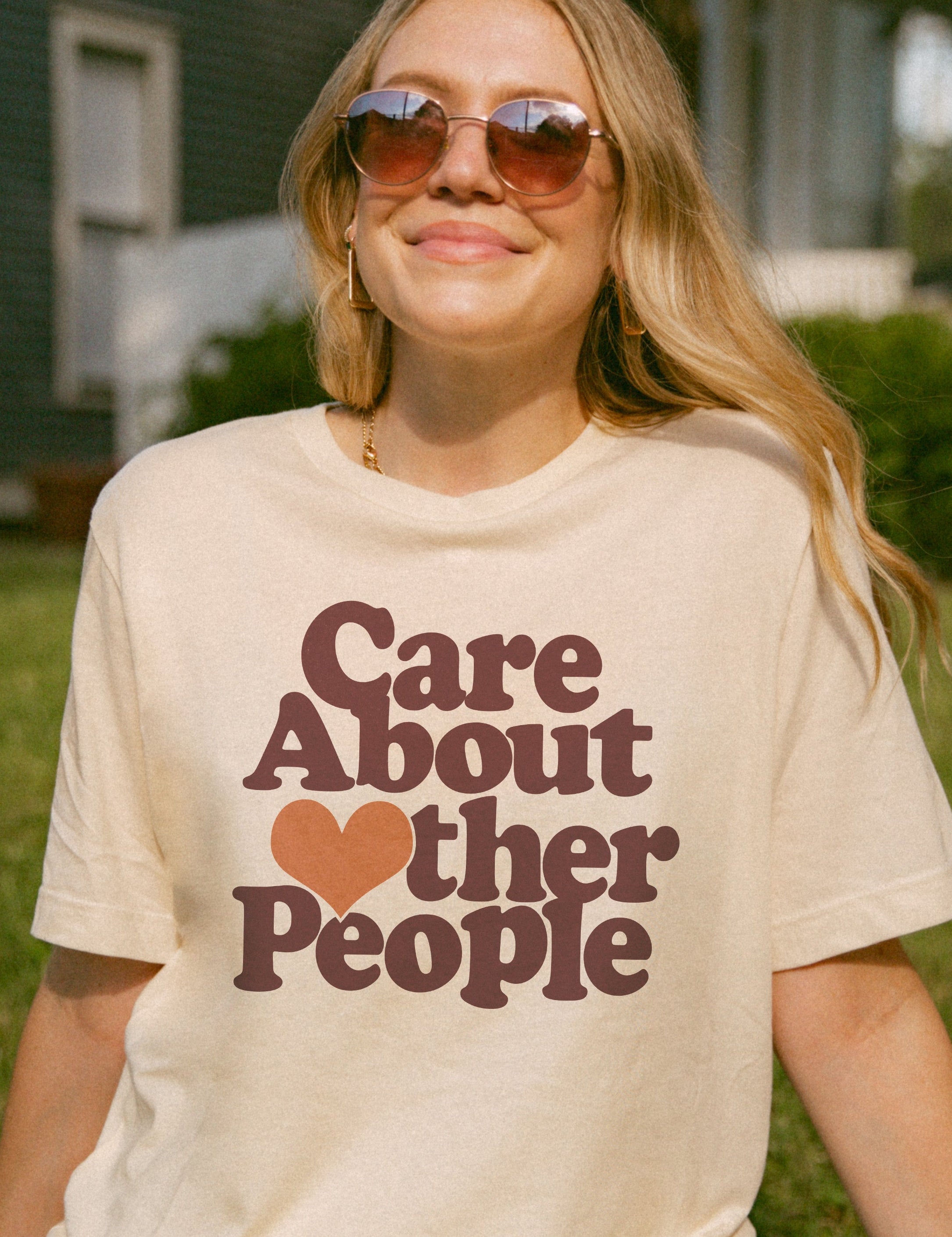 Person wearing a t-shirt with 'Care About Other People' text in a garden setting