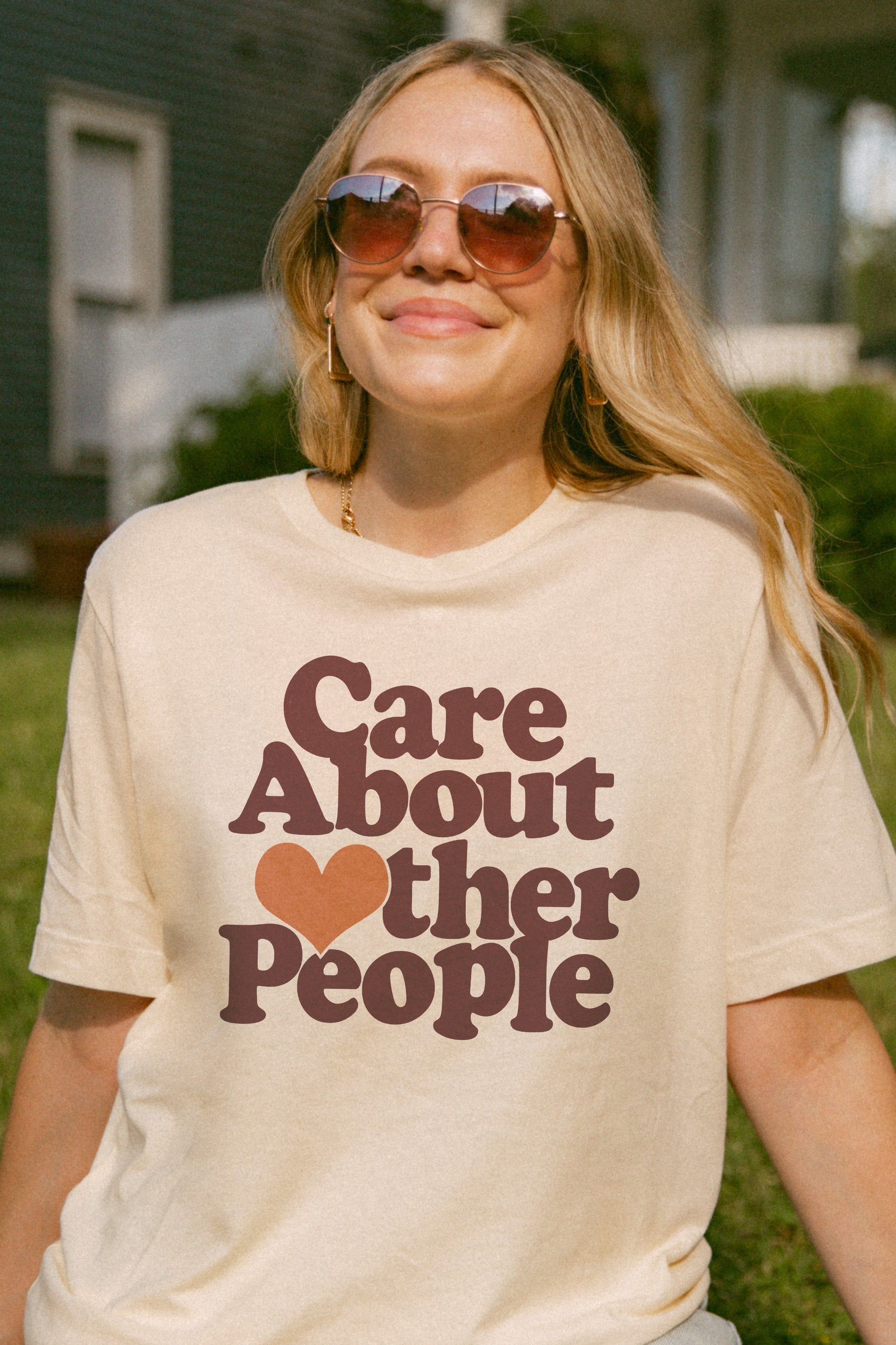 Person wearing a t-shirt with 'Care About Other People' text in a garden setting