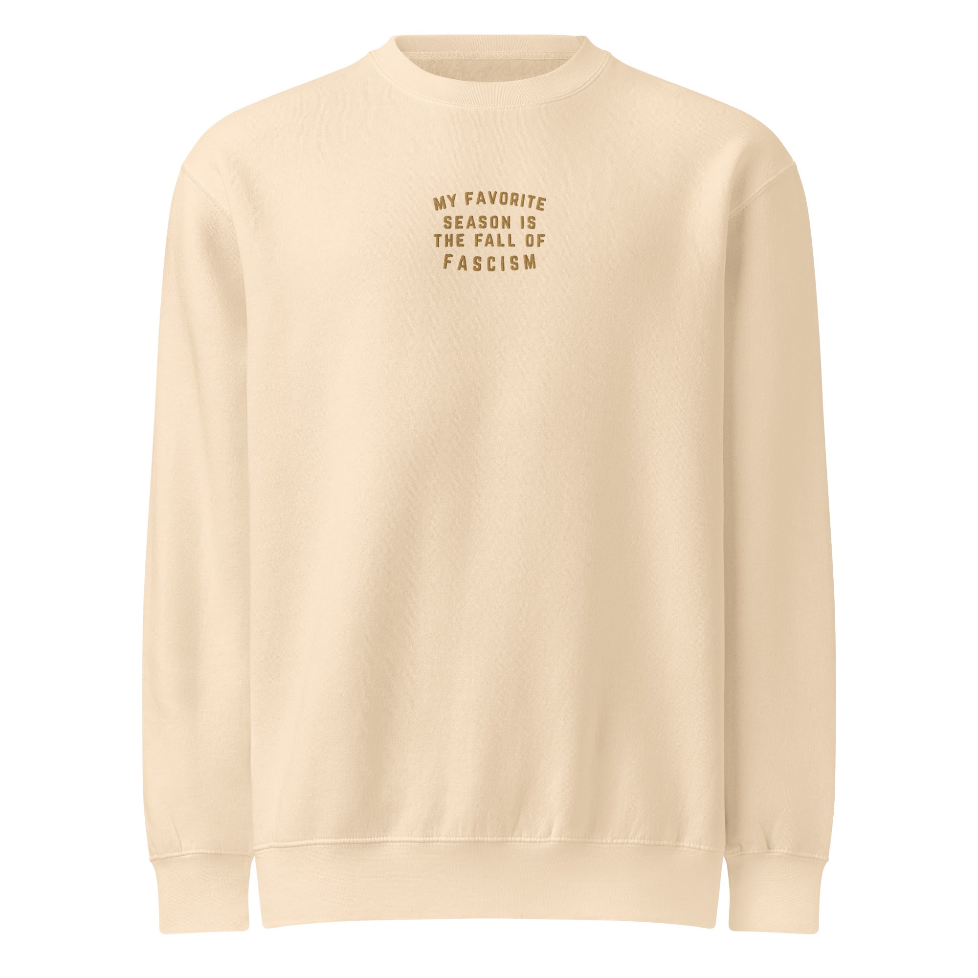 Beige sweatshirt with gold embroidered text that reads "my favorite season is the fall of fascism" on a white background