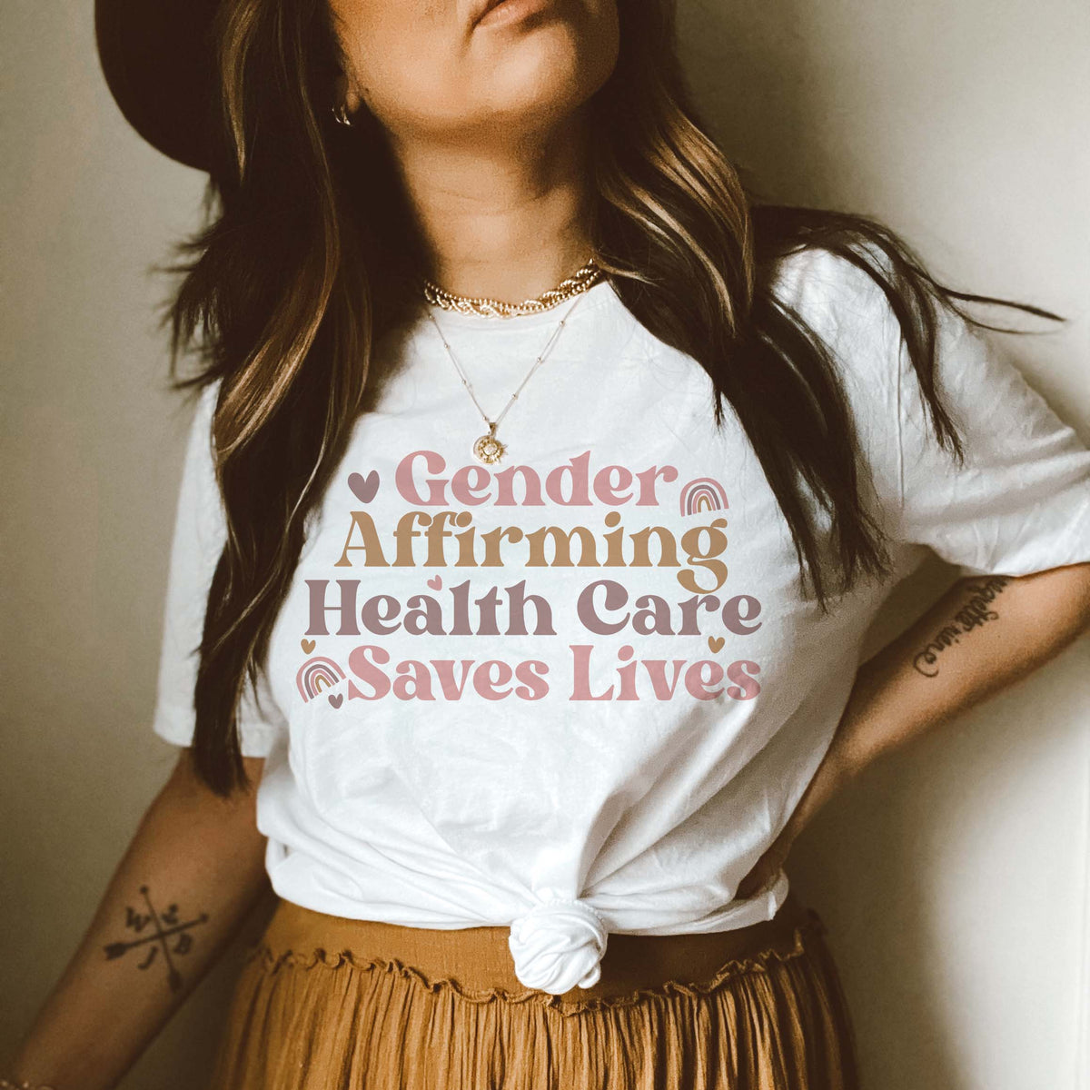 A woman with long hair wearing a white t shirt that reads "gender affirming healthcare saves lives"