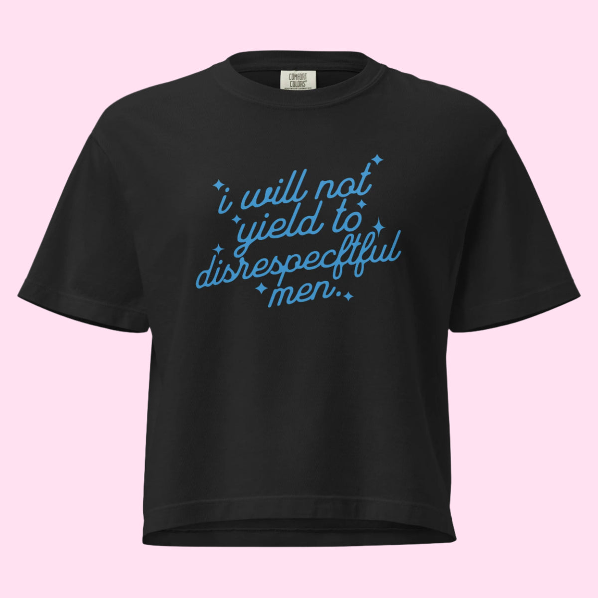 Flat lay of a black boxy crop tee displayed on a neutral background. The shirt features cursive blue text reading “I will not yield to disrespectful men” across the chest. Its heavyweight fabric and relaxed, boxy fit are shown. The Comfort Colors tag is featured.