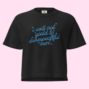 Flat lay of a black boxy crop tee displayed on a neutral background. The shirt features cursive blue text reading “I will not yield to disrespectful men” across the chest. Its heavyweight fabric and relaxed, boxy fit are shown. The Comfort Colors tag is featured.