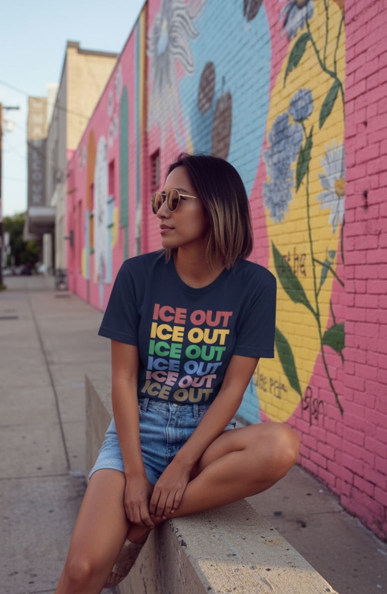 Woman sitting against a colorful mural on a pink wall wearing a t shirt that says ice out