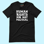 Flat lay of a black unisex t-shirt on a light blue background. The shirt features the bold white phrase “Human Rights Are Not Political” in all caps, centered on the front.
