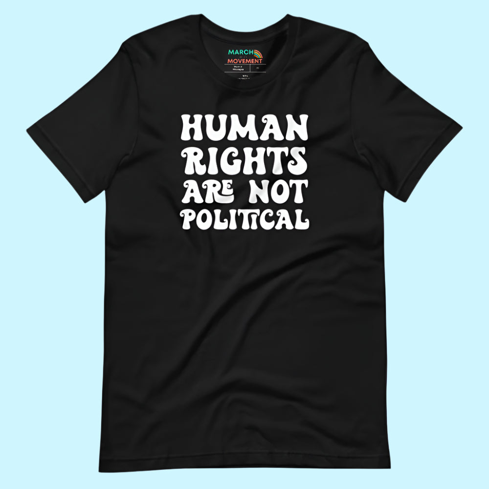 Flat lay of a black unisex t-shirt on a light blue background. The shirt features the bold white phrase “Human Rights Are Not Political” in all caps, centered on the front.
